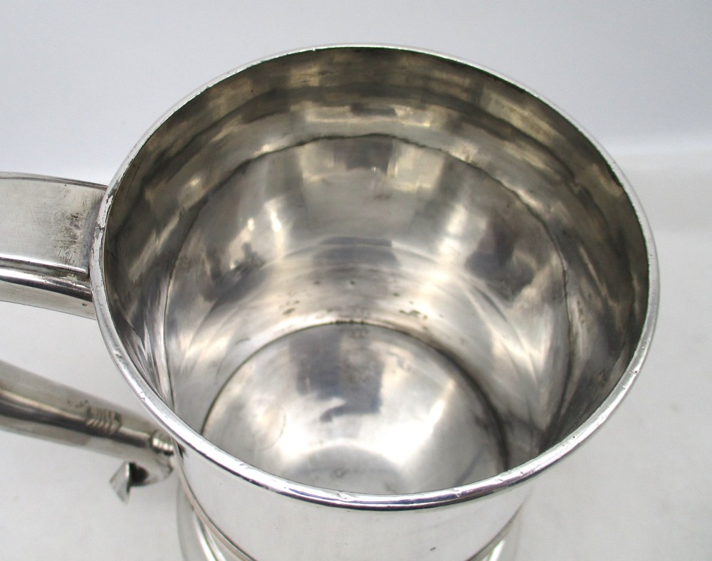 A Georgian Old Sheffield plated silver tankard featuring a reeded central band, a curved handle, and a stepped circular base. View V
