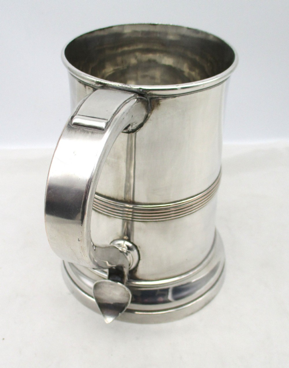 A Georgian Old Sheffield plated silver tankard featuring a reeded central band, a curved handle, and a stepped circular base. View VI