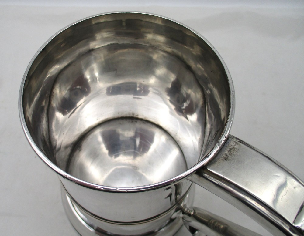 A Georgian Old Sheffield plated silver tankard featuring a reeded central band, a curved handle, and a stepped circular base. View IX