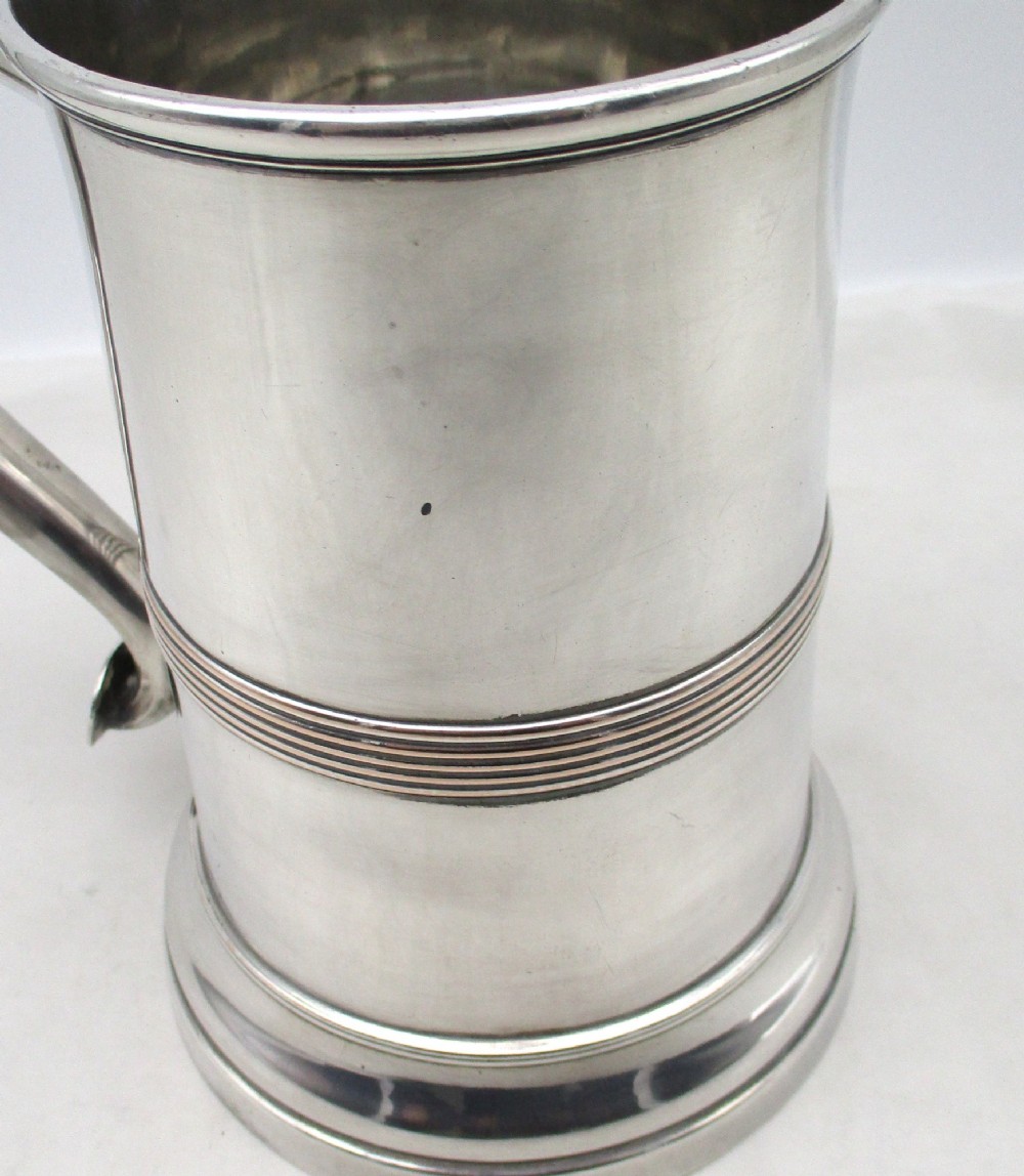 A Georgian Old Sheffield plated silver tankard featuring a reeded central band, a curved handle, and a stepped circular base. View XI