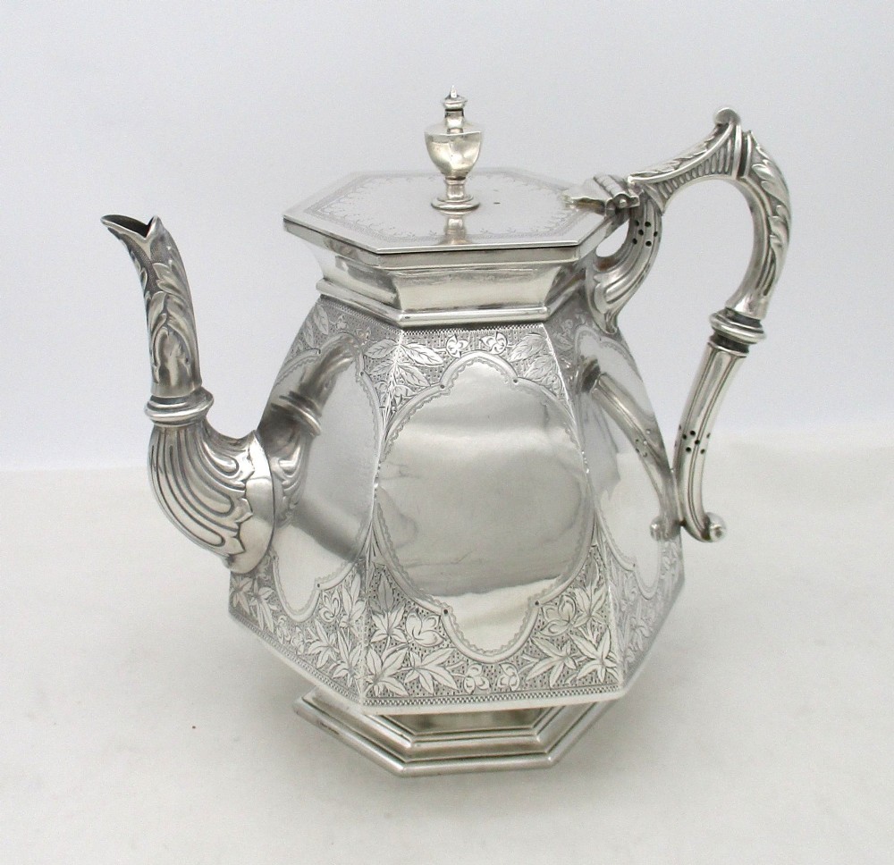 An octagonal silver plated teapot featuring floral engravings, a stylised handle with insulators, a shaped spout, and a finial lid.