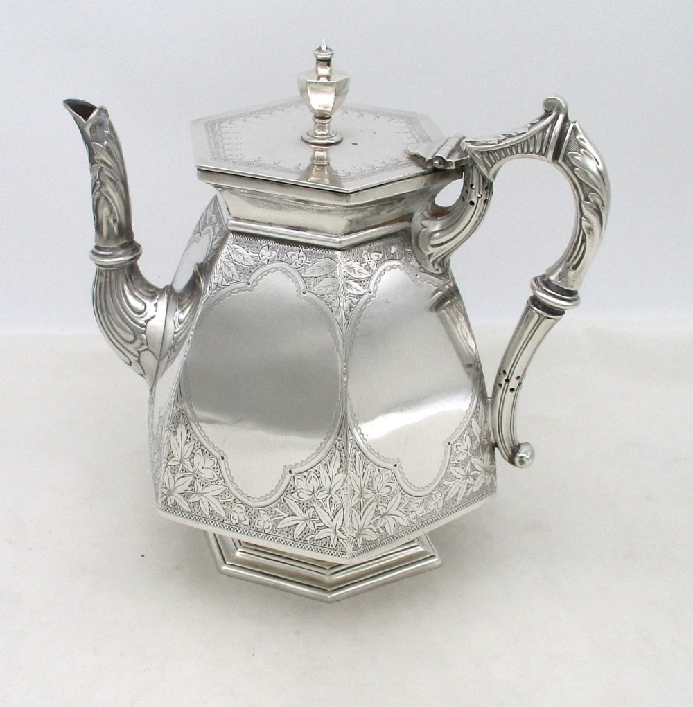 An octagonal silver plated teapot featuring floral engravings, a stylised handle with insulators, a shaped spout, and a finial lid. View III
