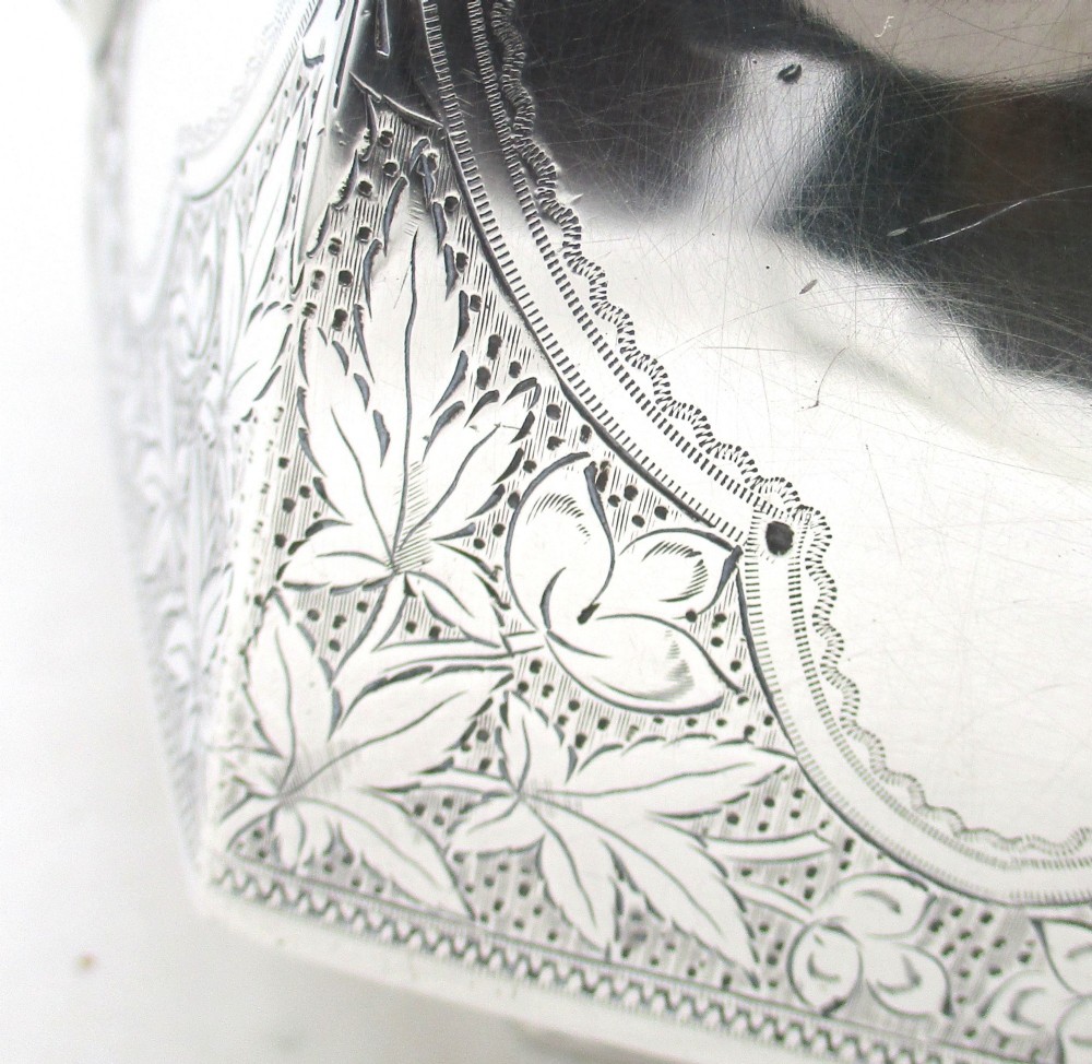 An octagonal silver plated teapot featuring floral engravings, a stylised handle with insulators, a shaped spout, and a finial lid. View VII