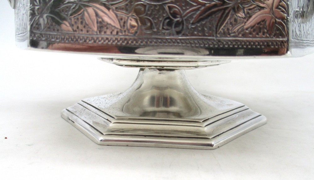 An octagonal silver plated teapot featuring floral engravings, a stylised handle with insulators, a shaped spout, and a finial lid. View VIII