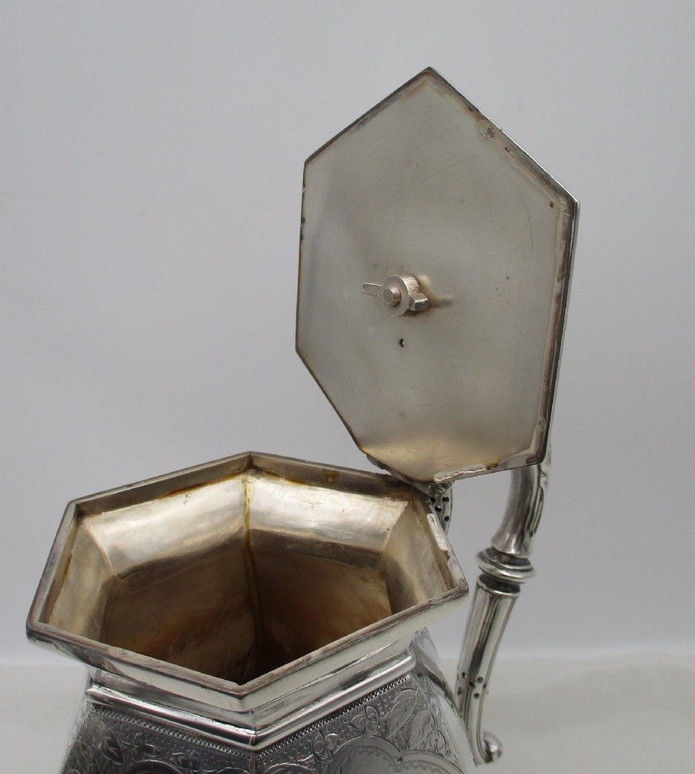 An octagonal silver plated teapot featuring floral engravings, a stylised handle with insulators, a shaped spout, and a finial lid. View IX