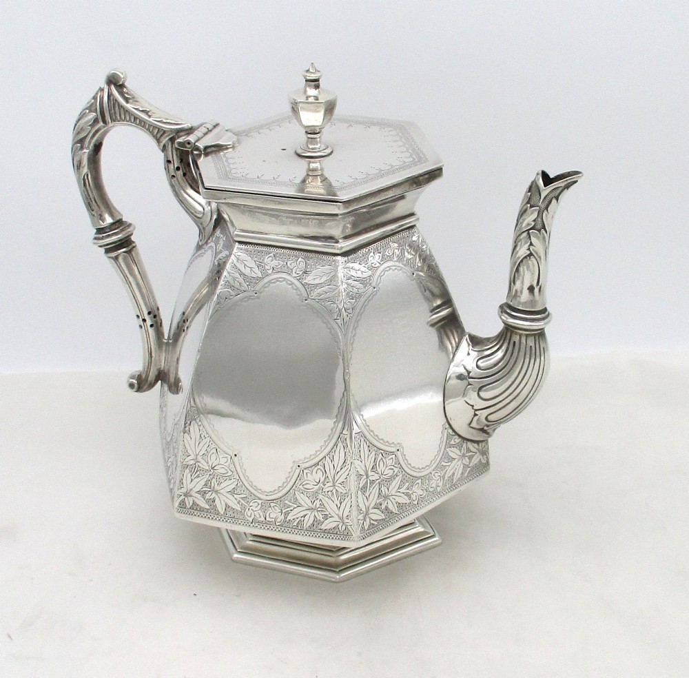 An octagonal silver plated teapot featuring floral engravings, a stylised handle with insulators, a shaped spout, and a finial lid. View X