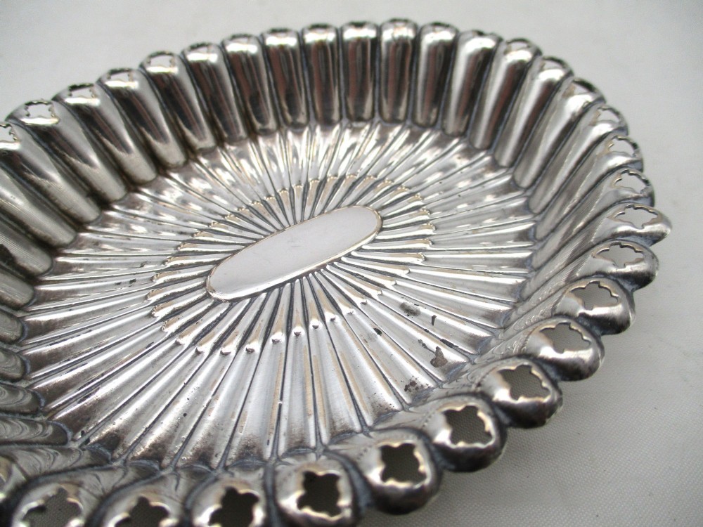 An 18th-century oval Old Sheffield Plated pin tray featuring fluted radiating panels, a smooth central oval, and a pierced scalloped rim. View VII