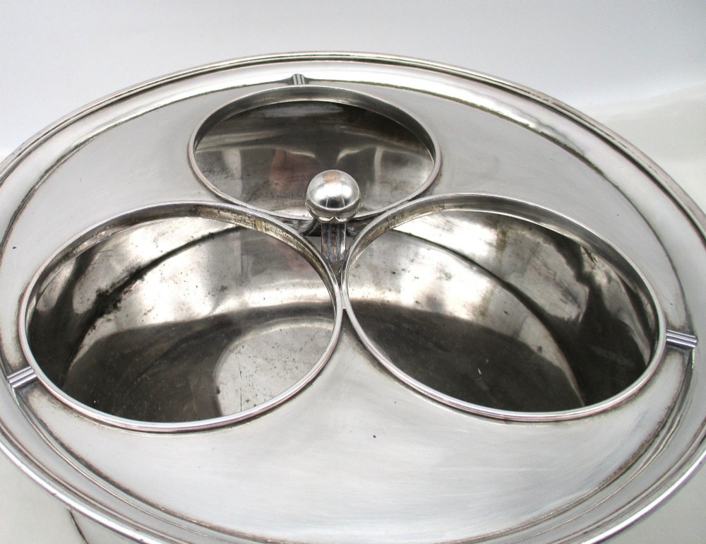 An oval Georgian silver-plated wine cooler designed to hold three bottles with a central finial handle. View IV