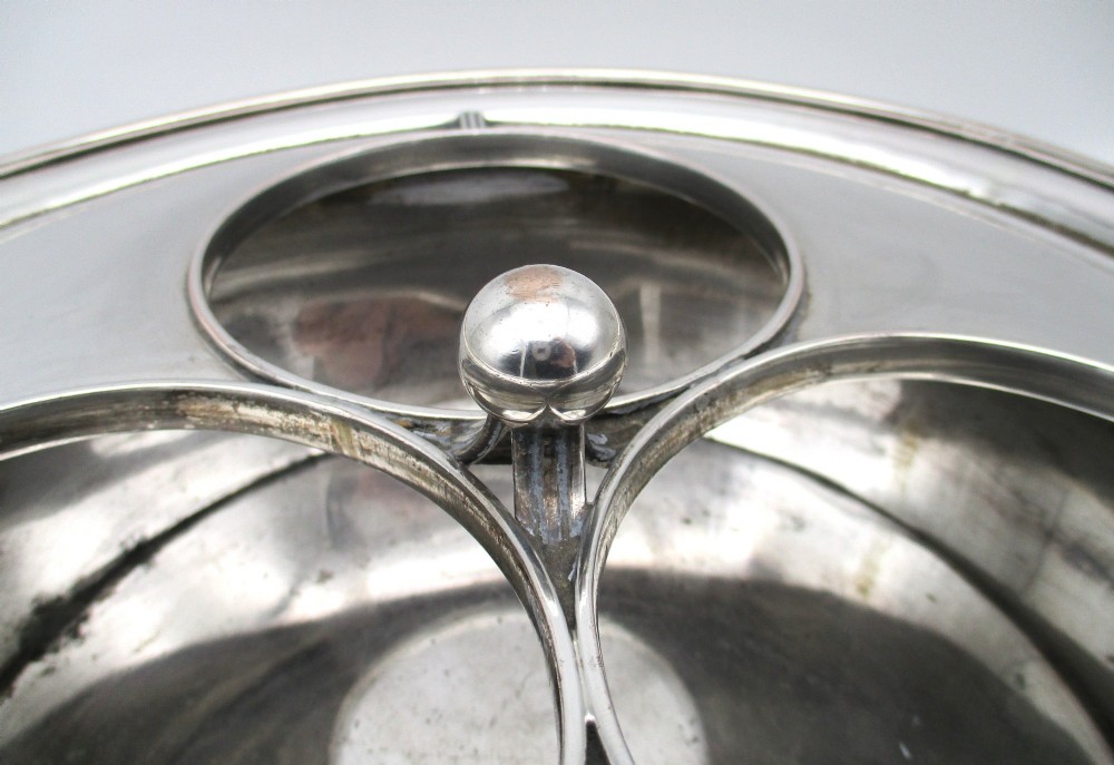 An oval Georgian silver-plated wine cooler designed to hold three bottles with a central finial handle. View V