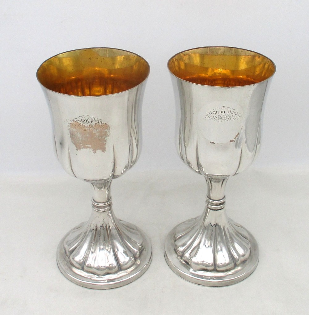A pair of silver-plated Old Sheffield chalices featuring fluted lower bowls, raised lobed bases, and gilded interiors engraved with chapel inscriptions.