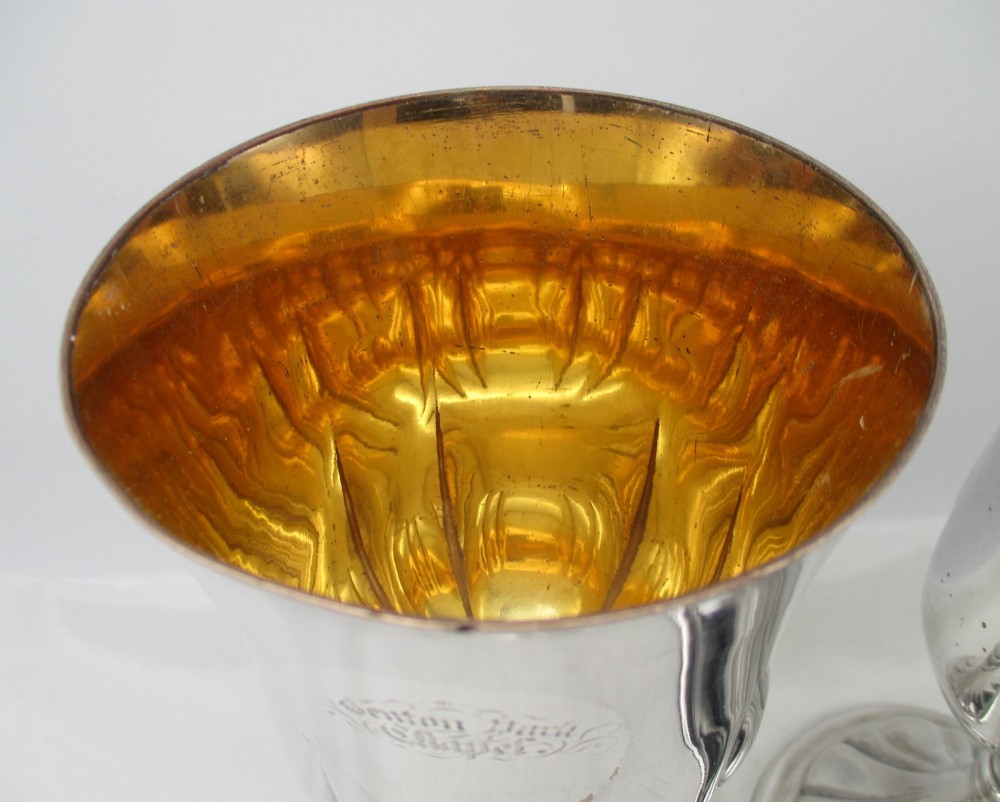 A pair of silver-plated Old Sheffield chalices featuring fluted lower bowls, raised lobed bases, and gilded interiors engraved with chapel inscriptions. View II