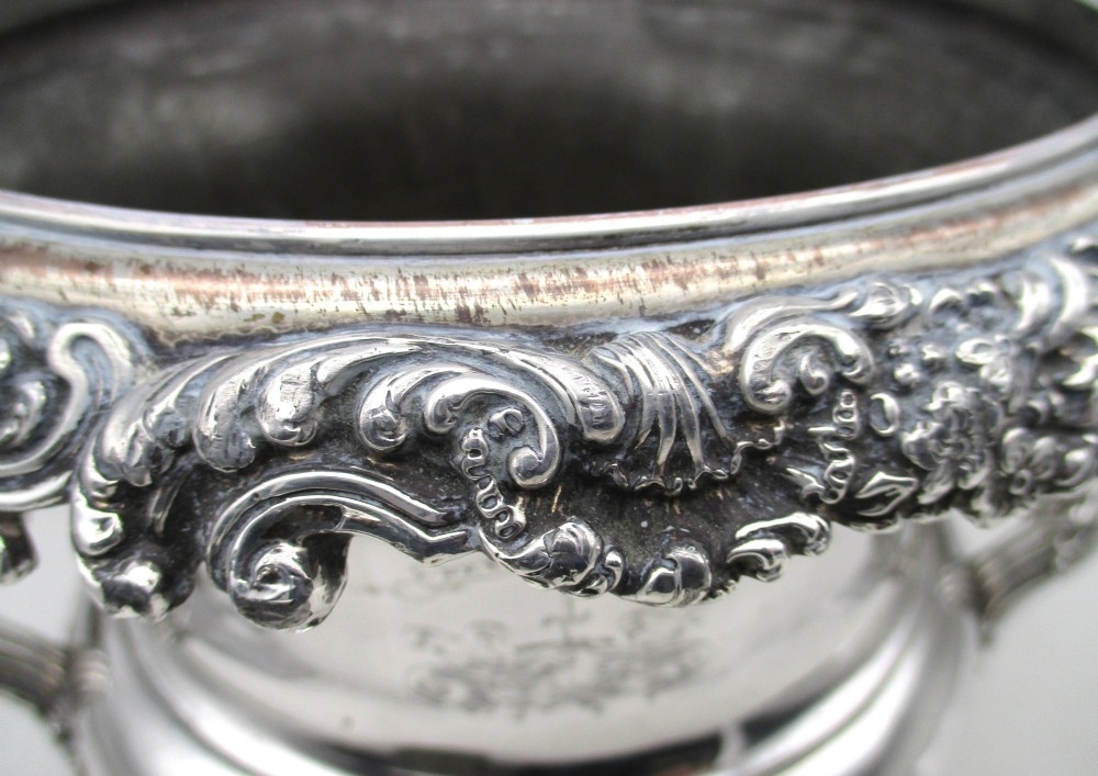 A Georgian silver-plated double-handled wine cooler featuring an engraved family crest, foliage borders, and a pedestal base. View VI