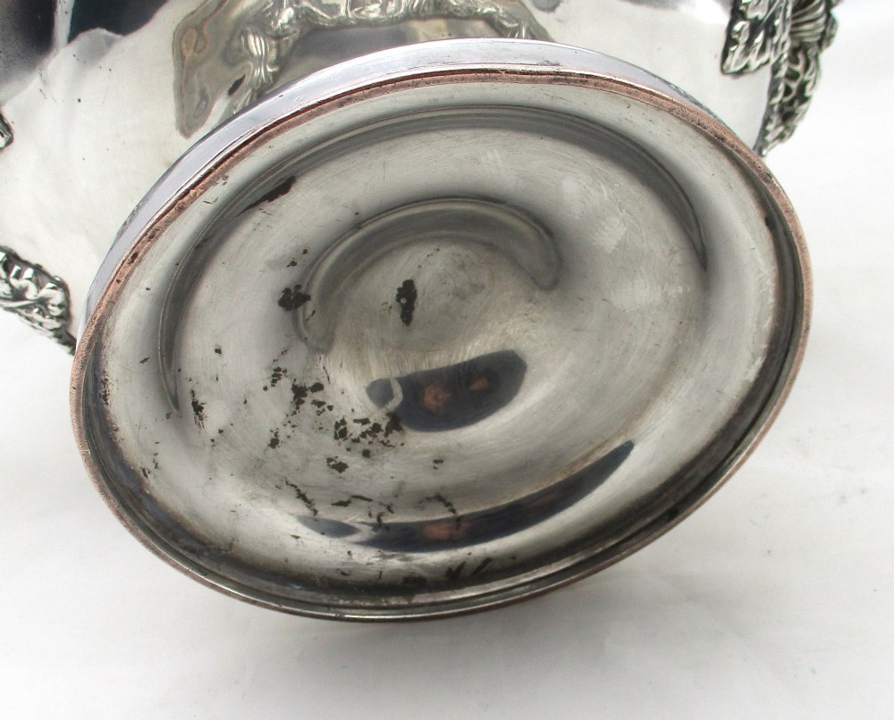 A Georgian silver-plated double-handled wine cooler featuring an engraved family crest, foliage borders, and a pedestal base. View XI