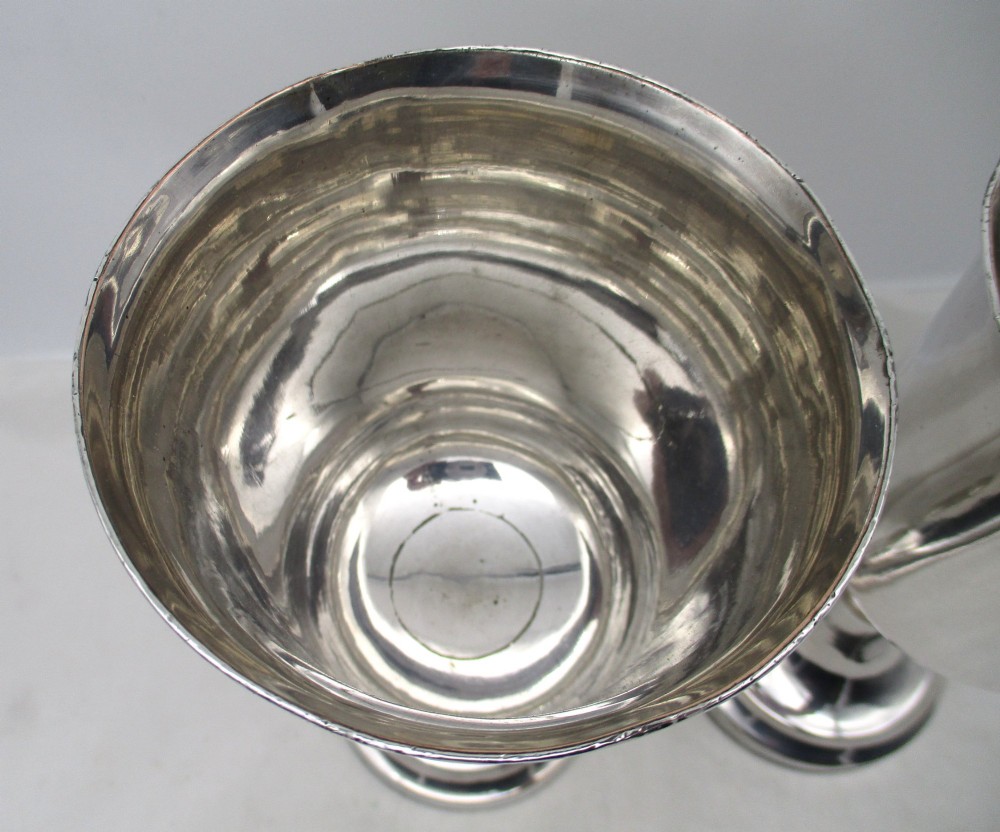 A pair of tall silver-plated church chalices featuring flared rims, knopped central stems, and stepped circular bases. View III