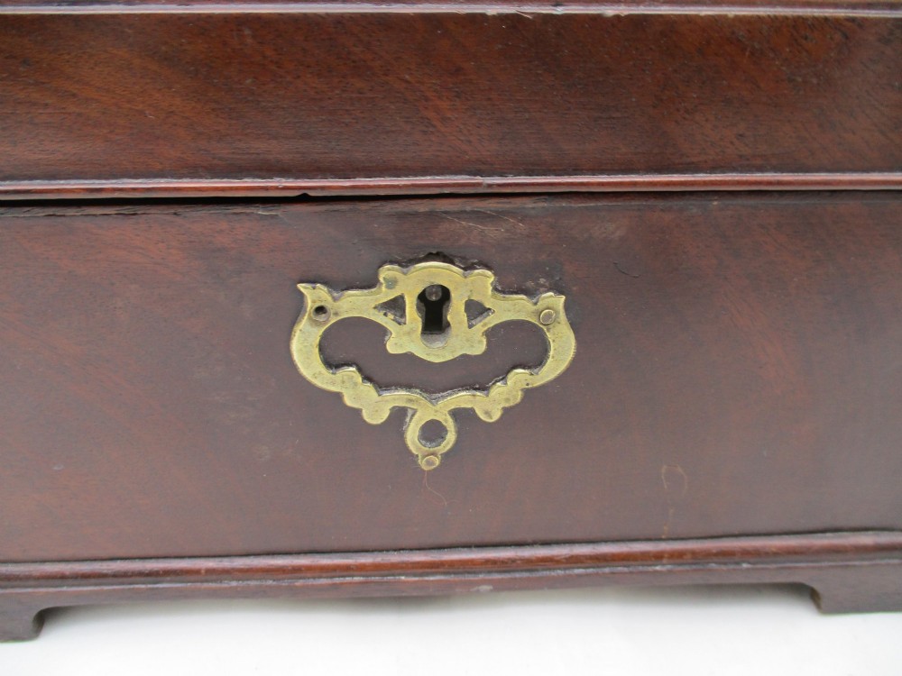 A rectangular George III mahogany tea caddy featuring a stepped hinged lid, a brass swan-neck handle, and a pierced brass keyhole escutcheon. View II