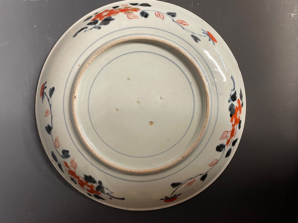 A circular Japanese Arita porcelain dish decorated with cobalt blue underglaze, iron red enamels, and gold leaf floral patterns surrounding a central urn motif. View III