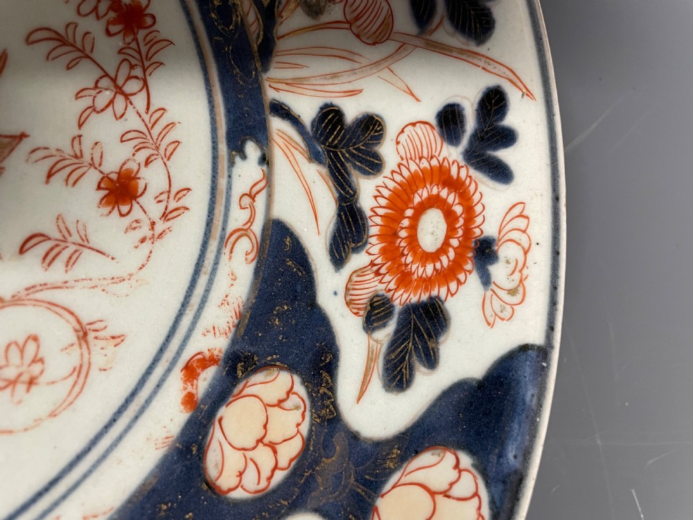 A circular Japanese Arita porcelain dish decorated with cobalt blue underglaze, iron red enamels, and gold leaf floral patterns surrounding a central urn motif. View V