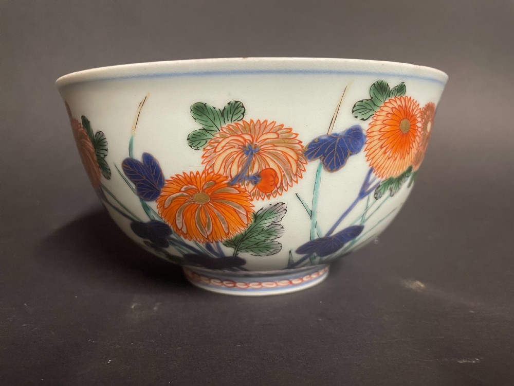 A circular Japanese Arita porcelain bowl seen from above, decorated with hand-painted underglaze blue and overglaze orange floral motifs. View II