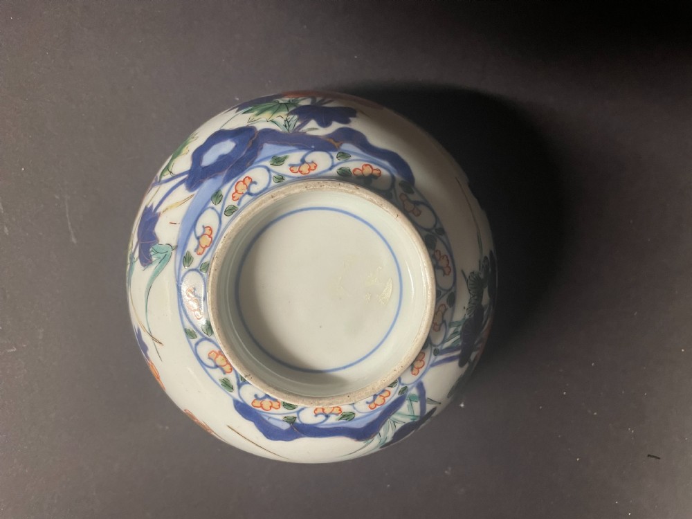 A circular Japanese Arita porcelain bowl seen from above, decorated with hand-painted underglaze blue and overglaze orange floral motifs. View V