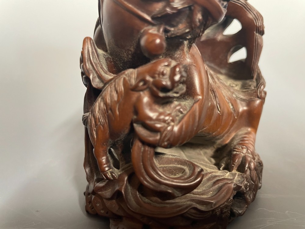 A hand-carved brown boxwood sculpture depicting a Chinese guardian lion, or foo dog, sitting on an integrated base alongside a small cub. View XII