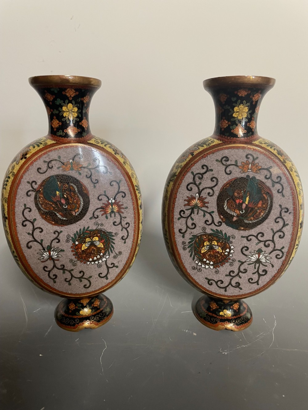 A pair of Japanese cloisonne enamel moon-flask vases featuring dragon medallions and floral scrollwork on flared bases. View III