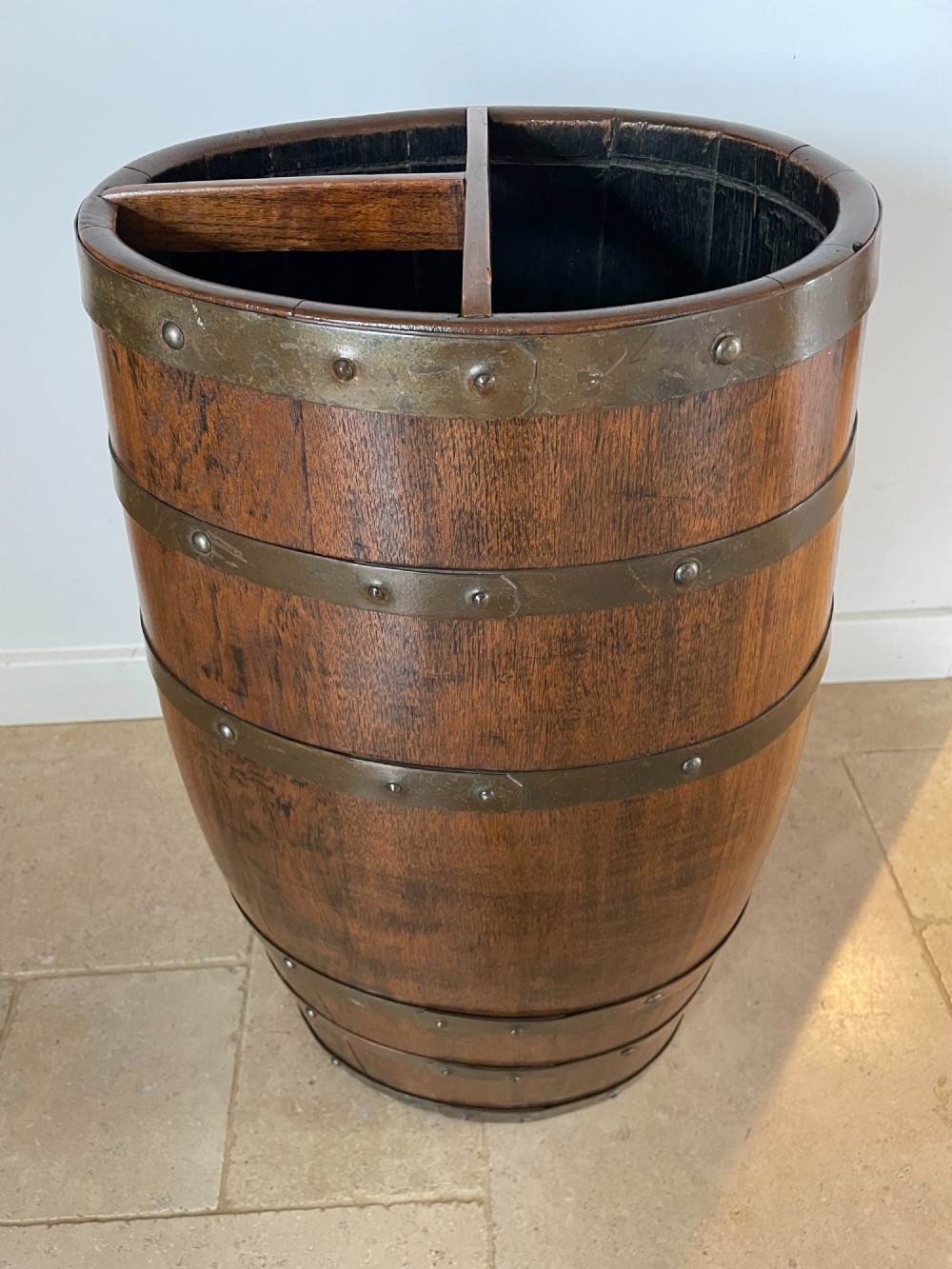 A barrel-shaped coopered oak umbrella stand featuring riveted metal bands and a central top divider. View V