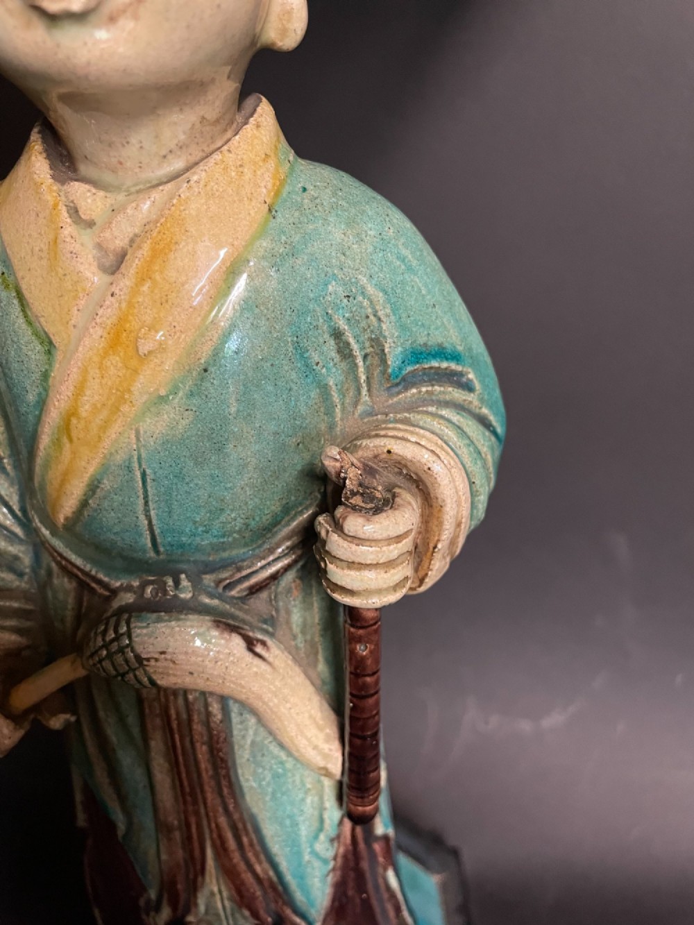 A Chinese porcelain figure table lamp featuring a green and brown glazed figurine on a black base topped with a tasseled fabric shade showing a painted landscape. View III