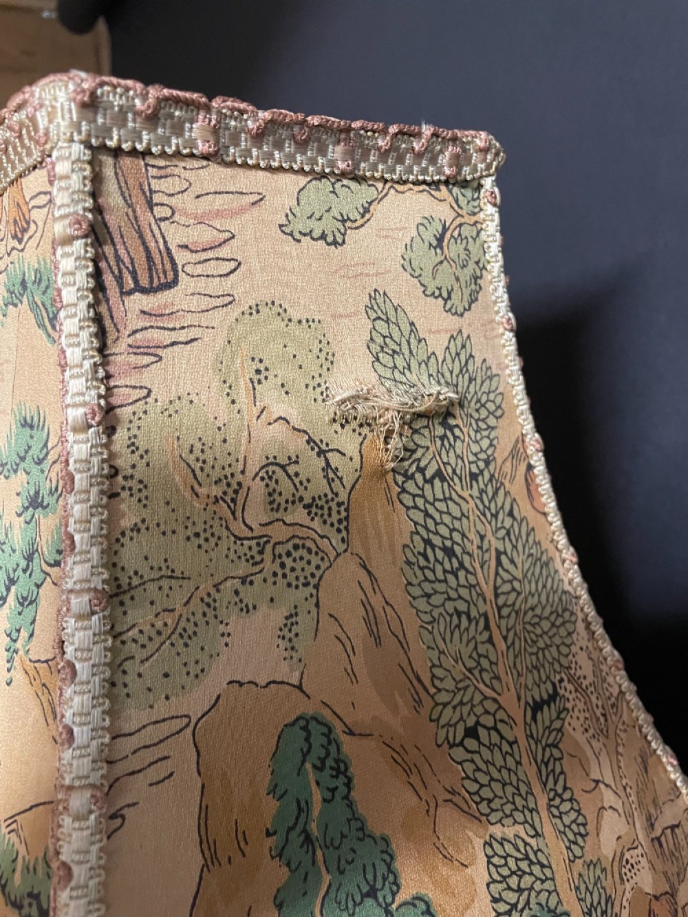 A Chinese porcelain figure table lamp featuring a green and brown glazed figurine on a black base topped with a tasseled fabric shade showing a painted landscape. View VIII