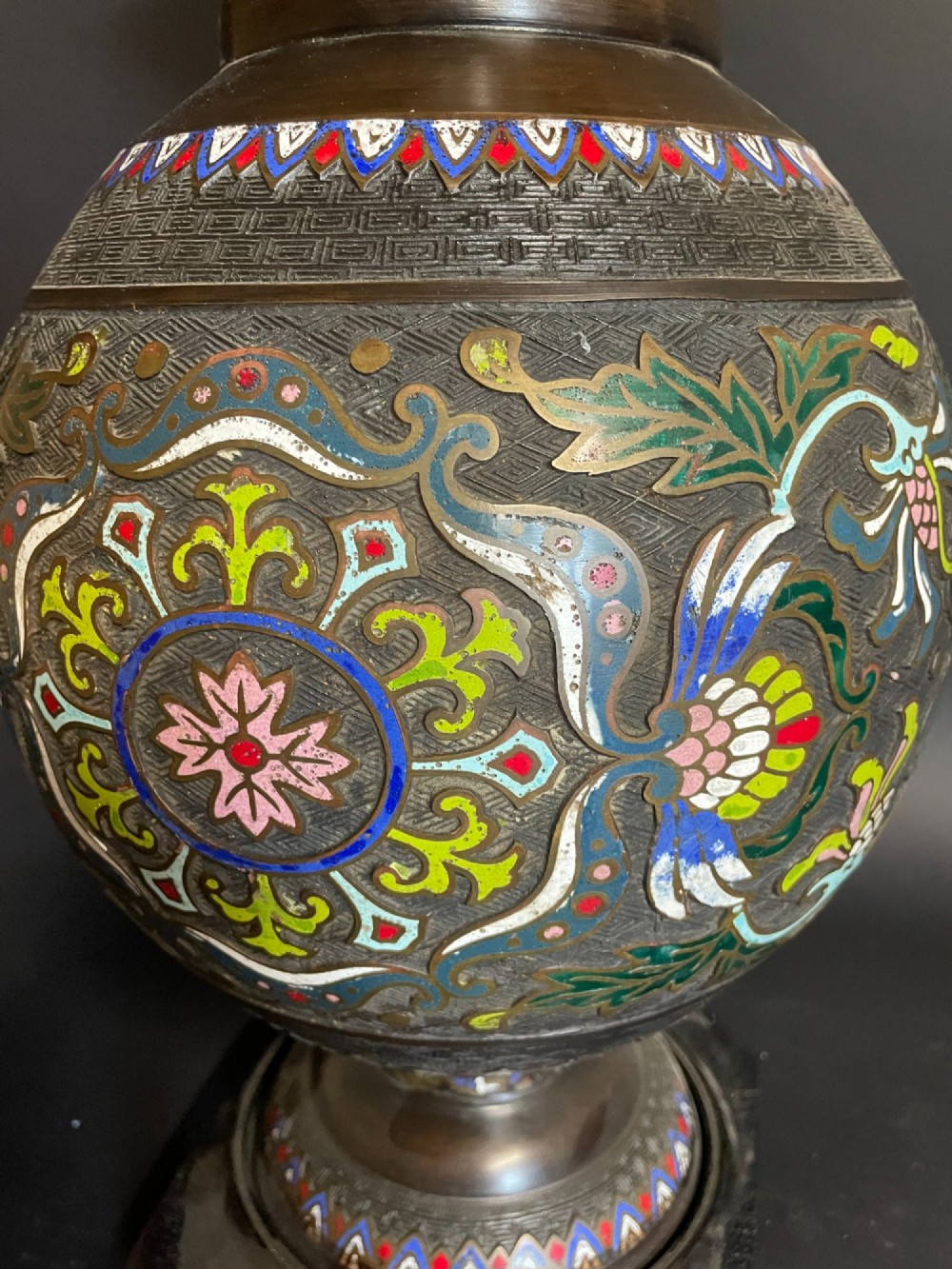 A dark bronze converted table lamp decorated with multicoloured floral enamel motifs and mounted on a footed metal base. View II