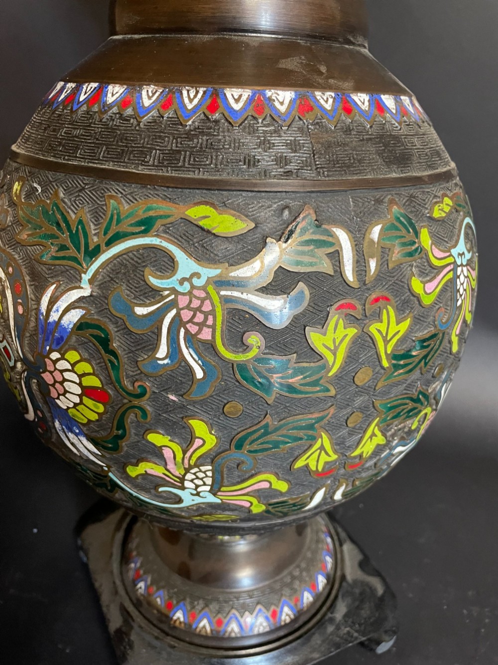 A dark bronze converted table lamp decorated with multicoloured floral enamel motifs and mounted on a footed metal base. View III
