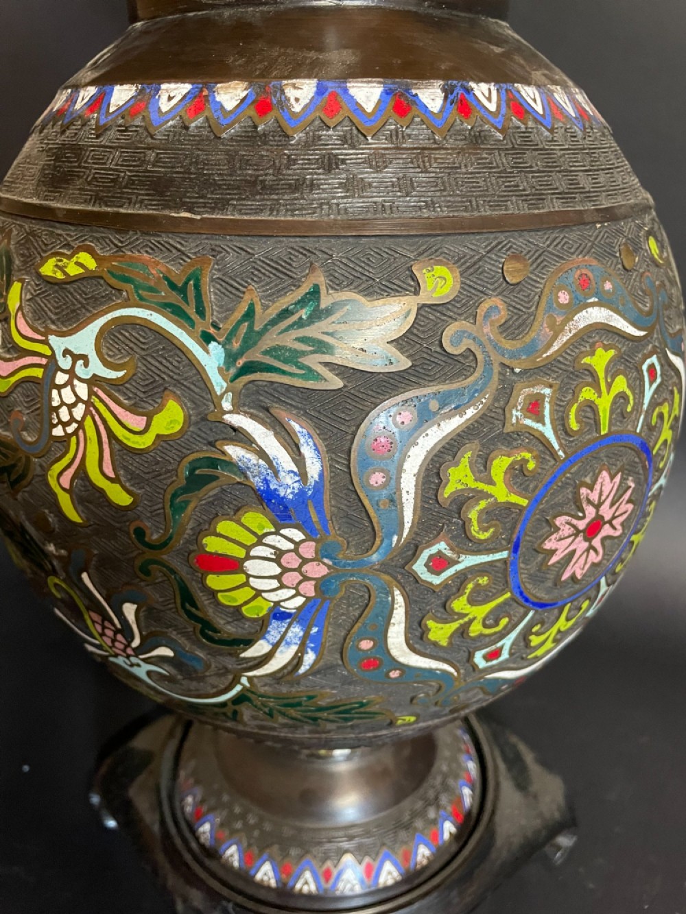 A dark bronze converted table lamp decorated with multicoloured floral enamel motifs and mounted on a footed metal base. View IV