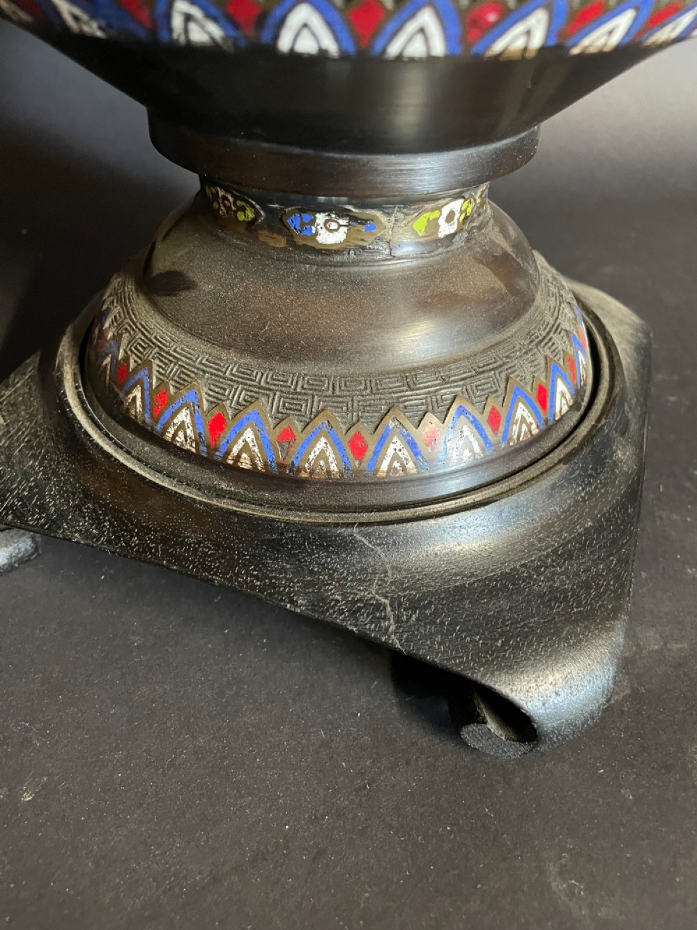 A dark bronze converted table lamp decorated with multicoloured floral enamel motifs and mounted on a footed metal base. View V