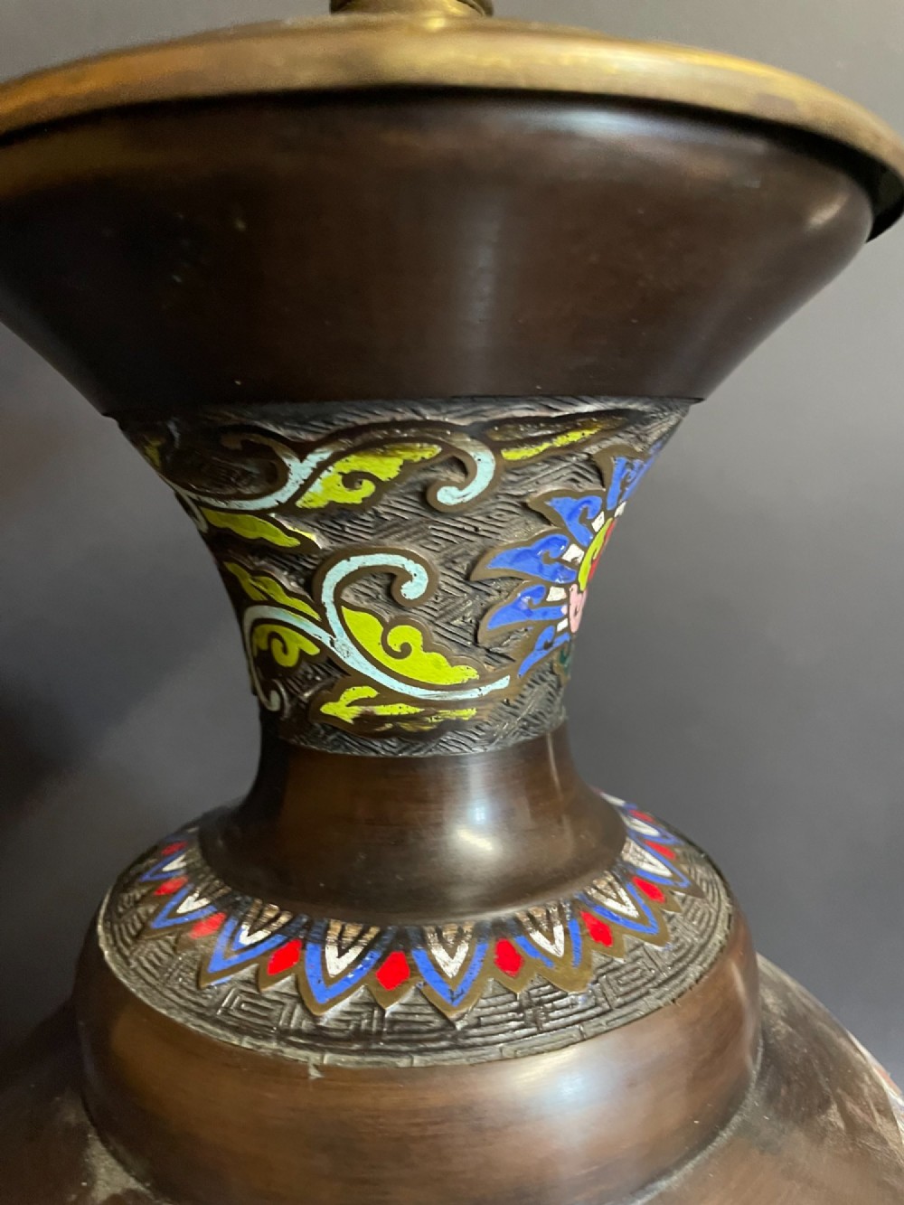 A dark bronze converted table lamp decorated with multicoloured floral enamel motifs and mounted on a footed metal base. View VI