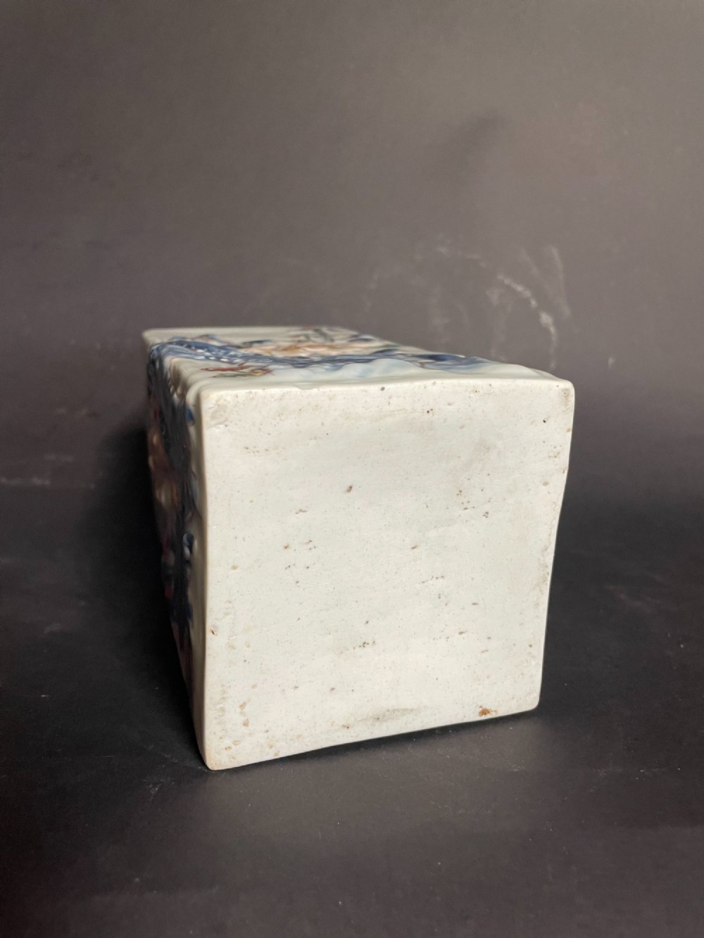 A rectangular off-white Japanese porcelain tokuri flask featuring relief carvings and hand-painted polychrome enamel depictions of a Shishi lion dog and floral foliage. View VII