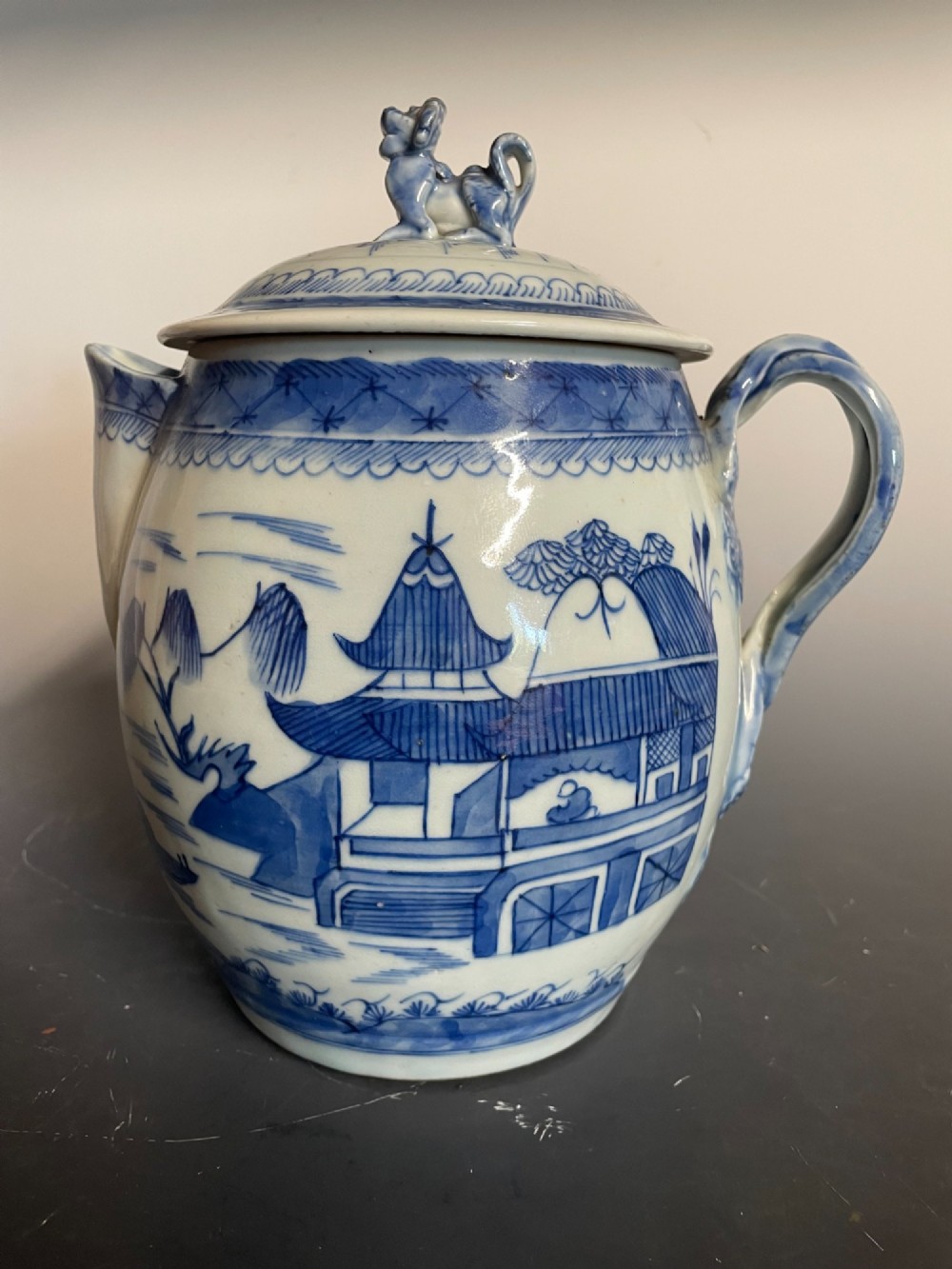 A blue and white Chinese export porcelain lidded jug featuring hand-painted pagoda landscape scenes and a foo dog lid finial.