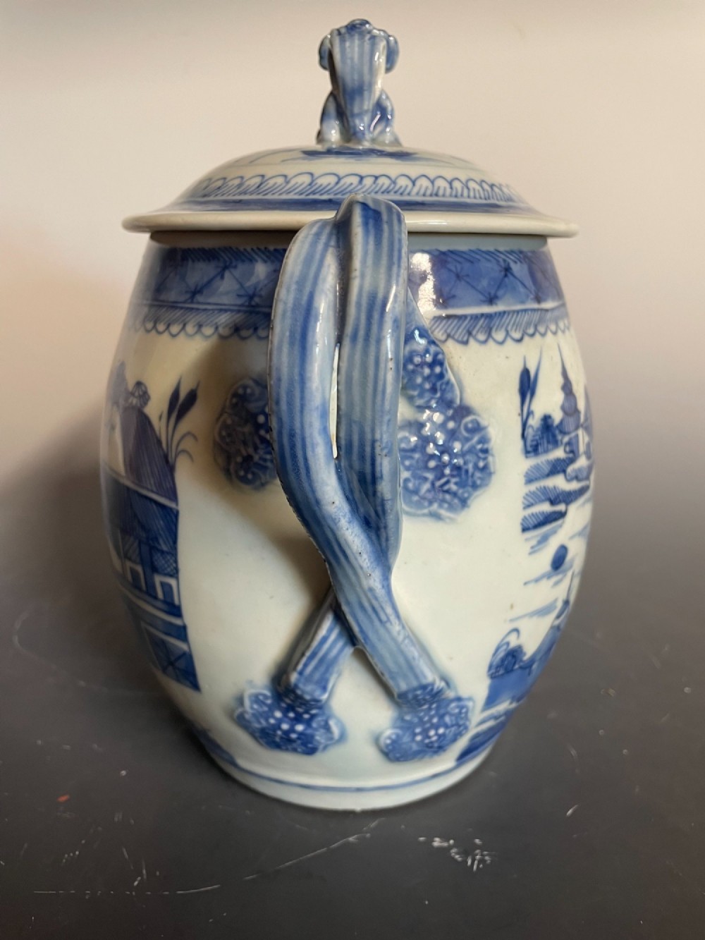 A blue and white Chinese export porcelain lidded jug featuring hand-painted pagoda landscape scenes and a foo dog lid finial. View II