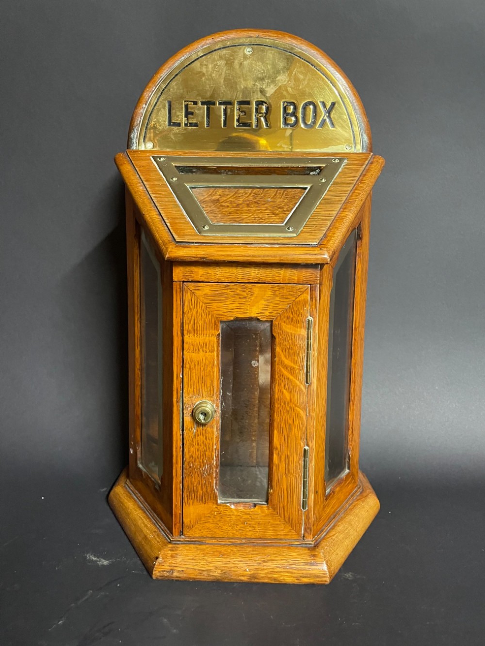 A Victorian oak tabletop letter box featuring brass fittings, a sloped aperture slot, glass side panels, and an arched brass top plate stamped LETTER BOX. View III