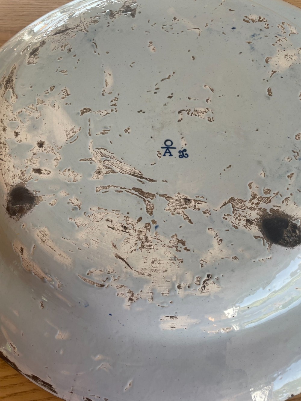 A circular Dutch Delft tin-glazed earthenware charger decorated in cobalt blue and white with a central pictorial tavern scene surrounded by ornate floral and cartouche borders. View X