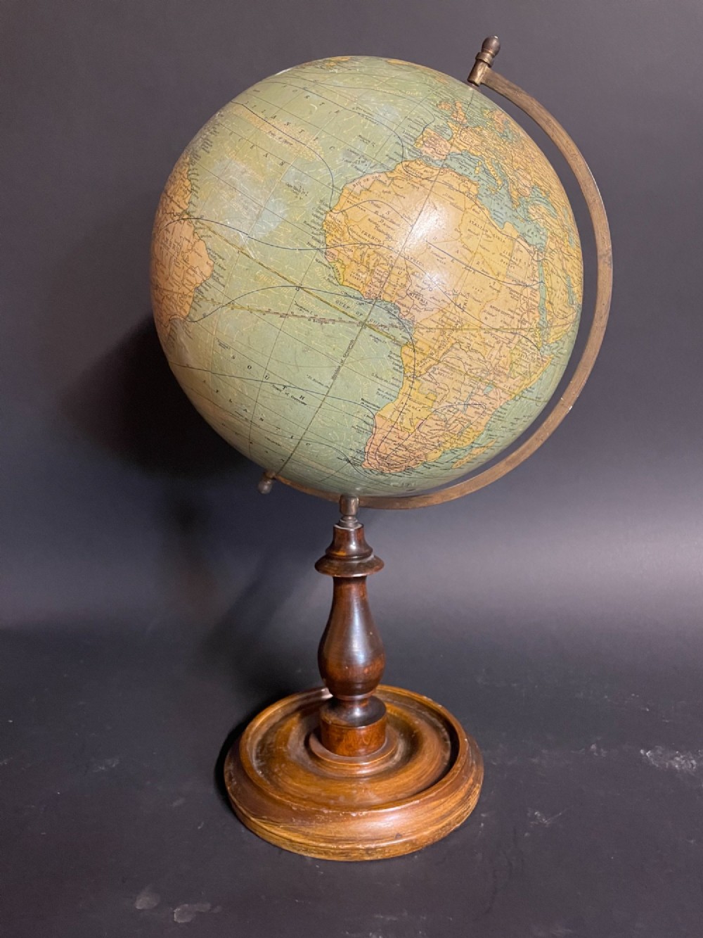 An antique terrestrial table globe mounted on a turned dark wood stand with a brass semi-meridian.
