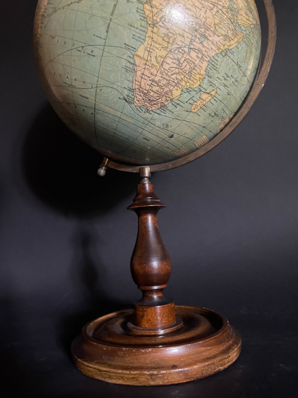 An antique terrestrial table globe mounted on a turned dark wood stand with a brass semi-meridian. View III
