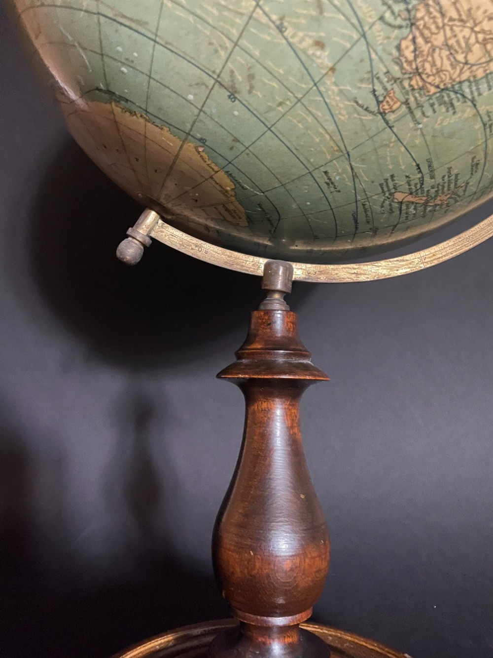 An antique terrestrial table globe mounted on a turned dark wood stand with a brass semi-meridian. View VII