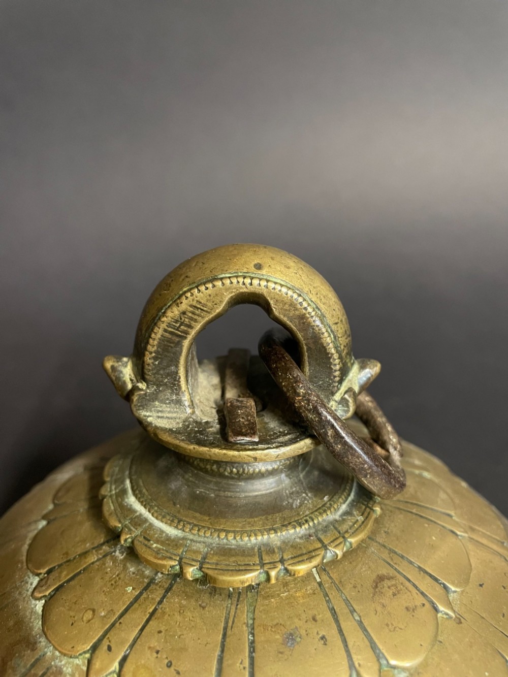 A dome-shaped Sino-Tibetan bronze bell featuring relief lotus petal decoration at the top collar and an iron attachment ring. View II