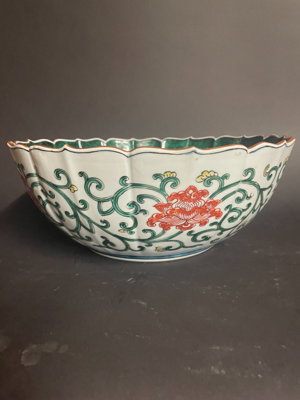 A fluted Japanese porcelain bowl with a scalloped edge, decorated with a central painted green dragon and ornate enamel borders. View III