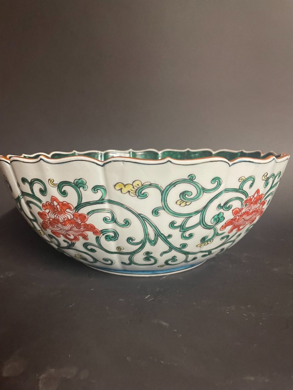 A fluted Japanese porcelain bowl with a scalloped edge, decorated with a central painted green dragon and ornate enamel borders. View IV