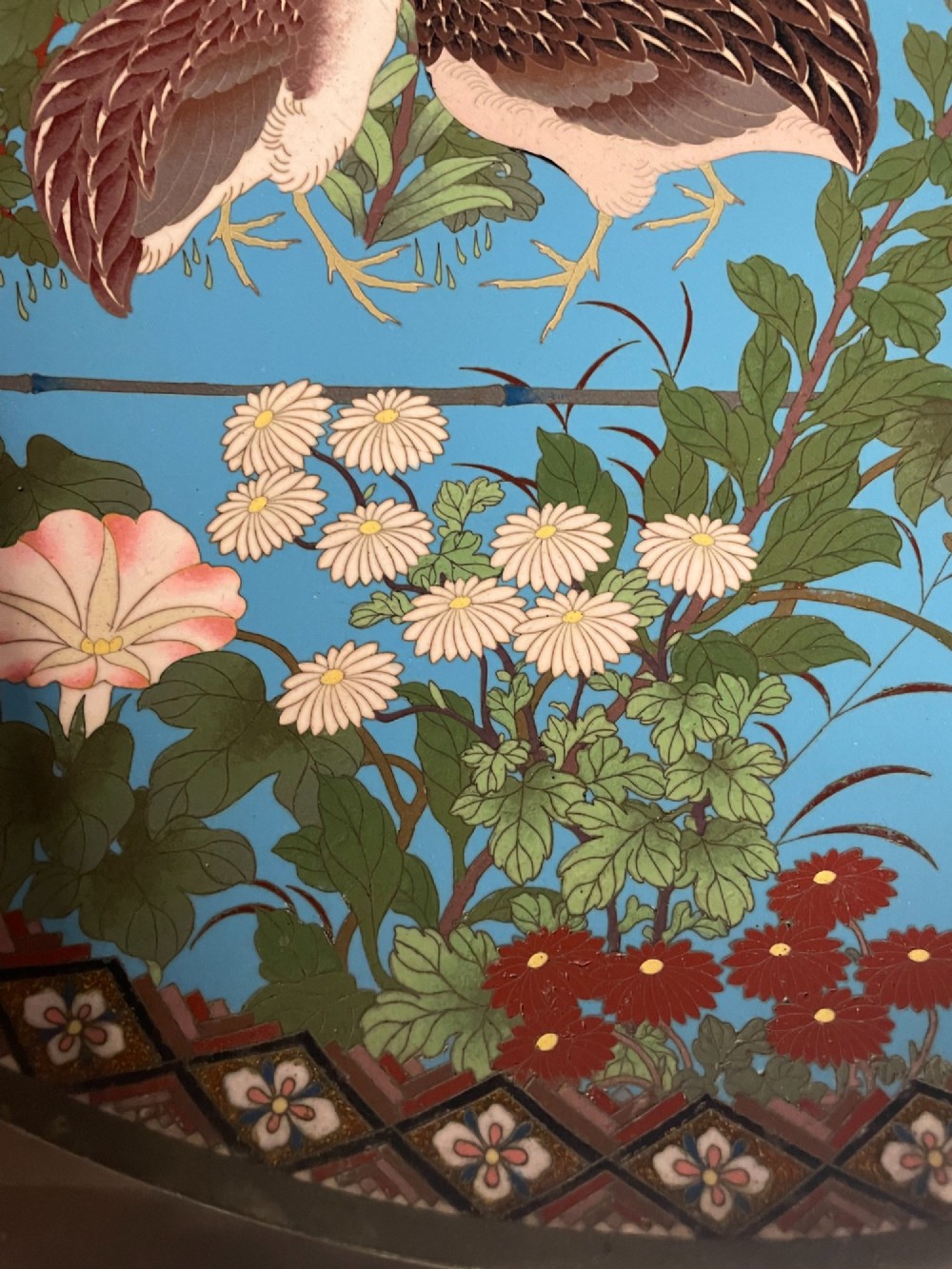 A circular Japanese cloisonne enamel charger depicting quails among chrysanthemums and lilies against a sky blue background with a patterned geometric border. View V