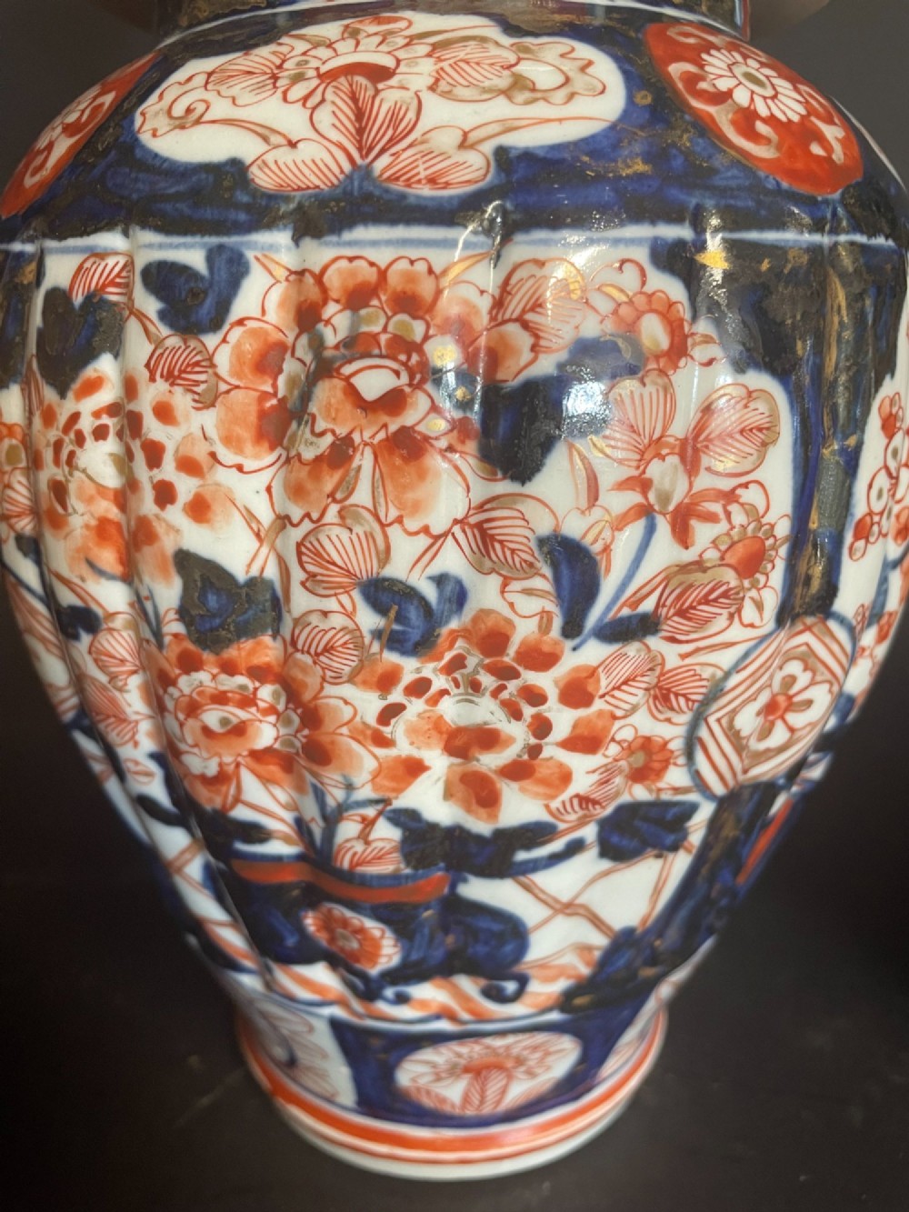 A pair of ribbed porcelain lidded jars decorated in a Japanese Imari pattern of cobalt blue, iron red, and gilt floral motifs with domed covers. View II