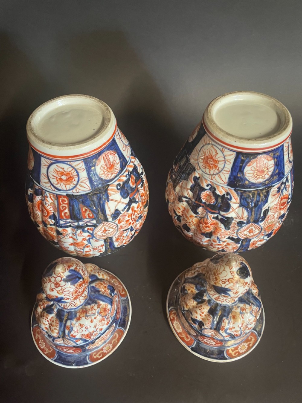 A pair of ribbed porcelain lidded jars decorated in a Japanese Imari pattern of cobalt blue, iron red, and gilt floral motifs with domed covers. View VI