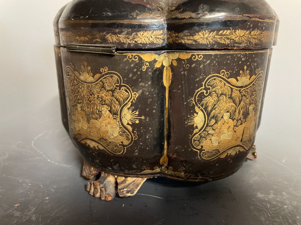 A lobed black lacquer Chinese export tea caddy decorated with gold painted figural scenes, featuring a brass escutcheon and carved feet. View VI