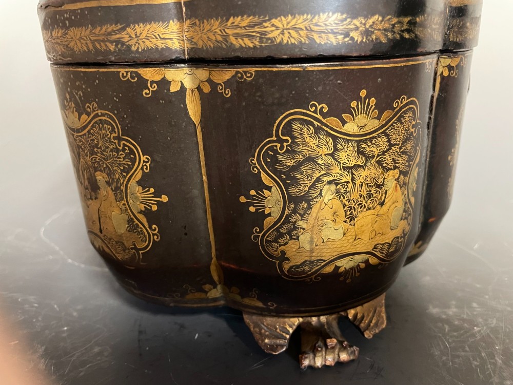 A lobed black lacquer Chinese export tea caddy decorated with gold painted figural scenes, featuring a brass escutcheon and carved feet. View VII