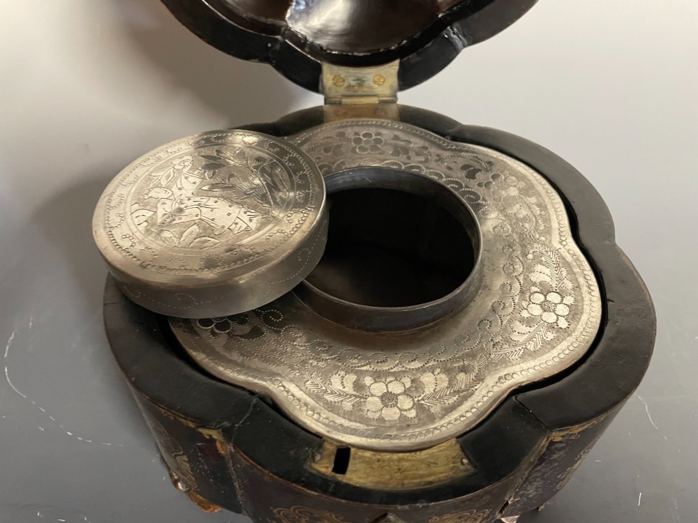 A lobed black lacquer Chinese export tea caddy decorated with gold painted figural scenes, featuring a brass escutcheon and carved feet. View IX